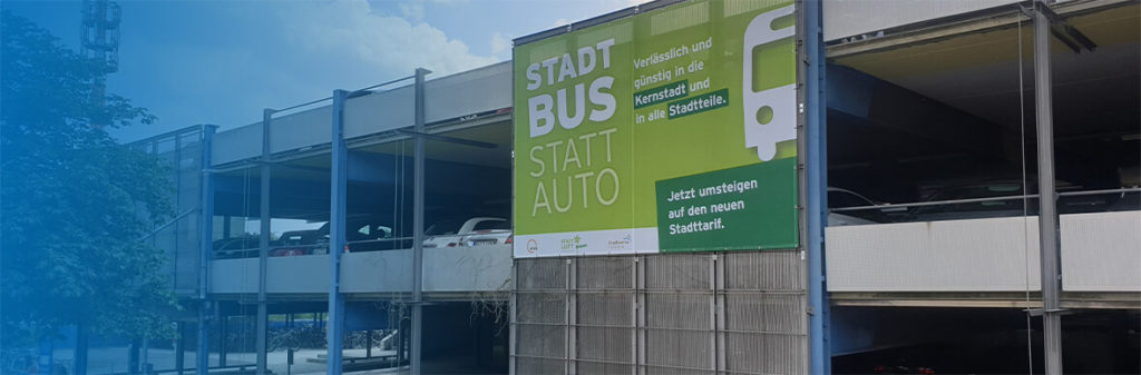 Parkdeck mit Werbeplakat mit Aufschrift Stadtbus statt Auto